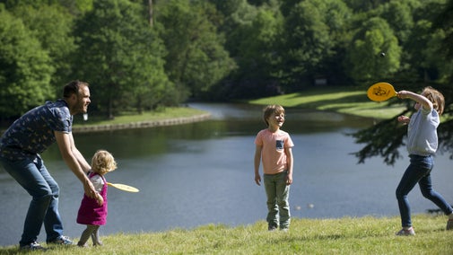 A family playing a game by the lake at Claremont Landscape Garden, Surrey.